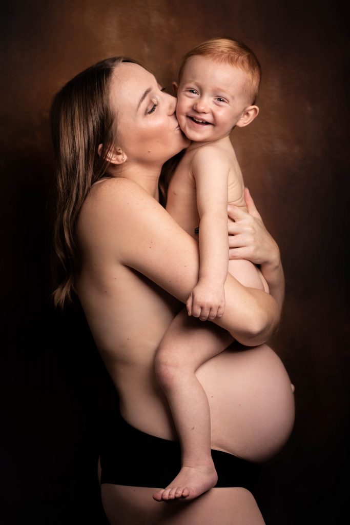 Future maman posant avec son garçon ainé lors d'une séance grossesse artistique